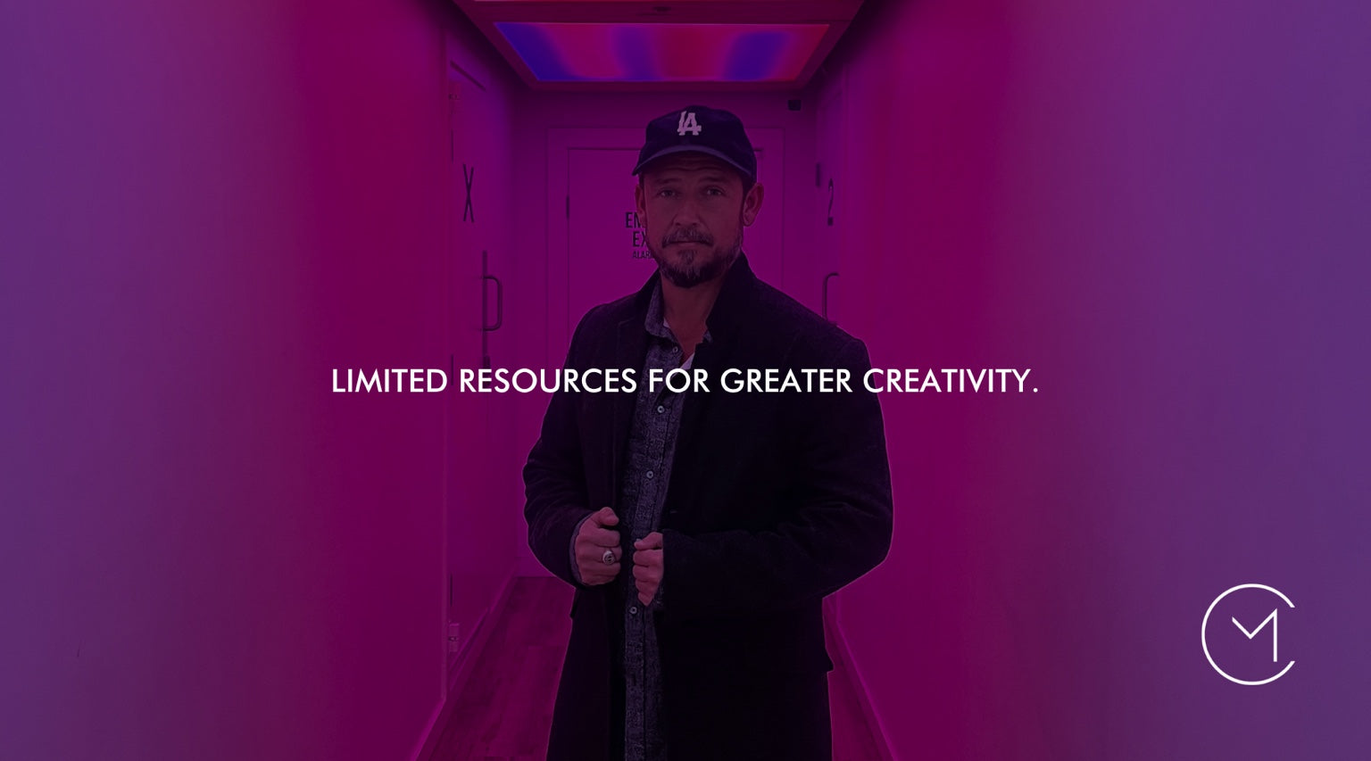 A man stands in a vivid purple hallway, illustrating how limited resources and constraints can encourage greater creativity.