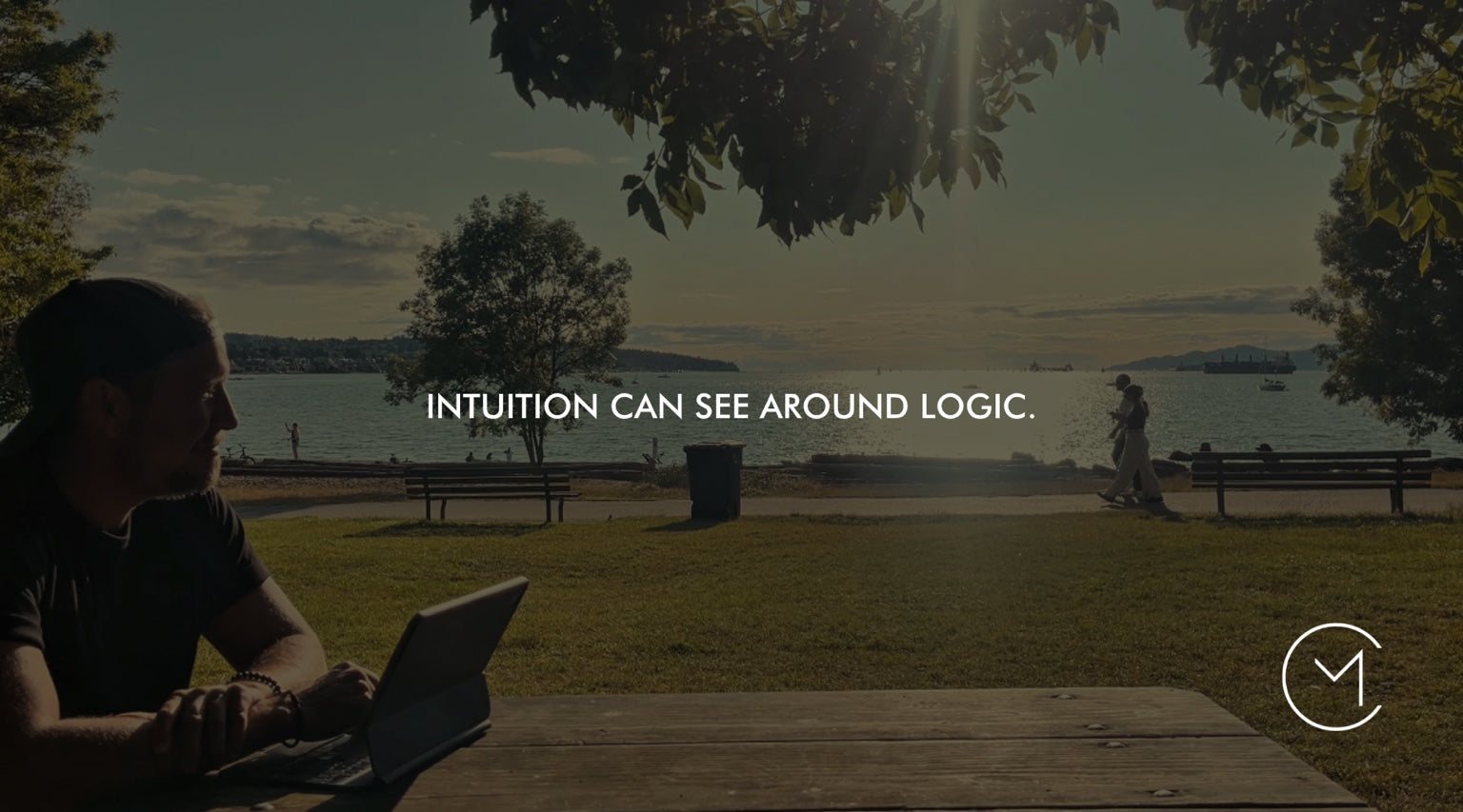 A man sits with a tablet beside the water, illustrating the relationship between intuition, rational thinking and decision-making.