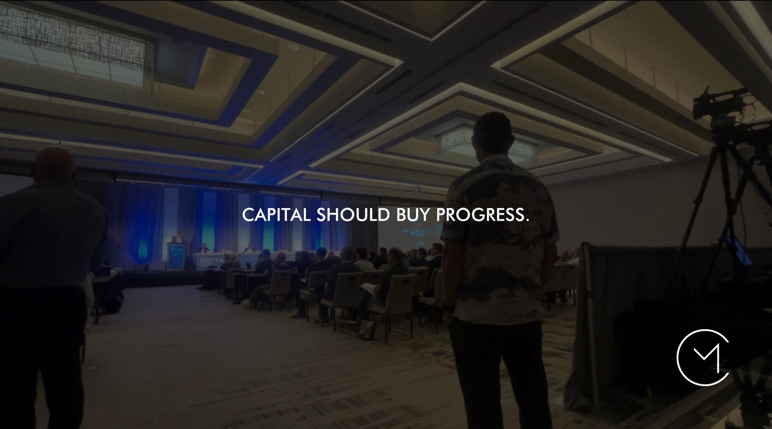 A man enters a capital markets conference, illustrating how capital should fund progress through the lifecycle of a small-cap public company.