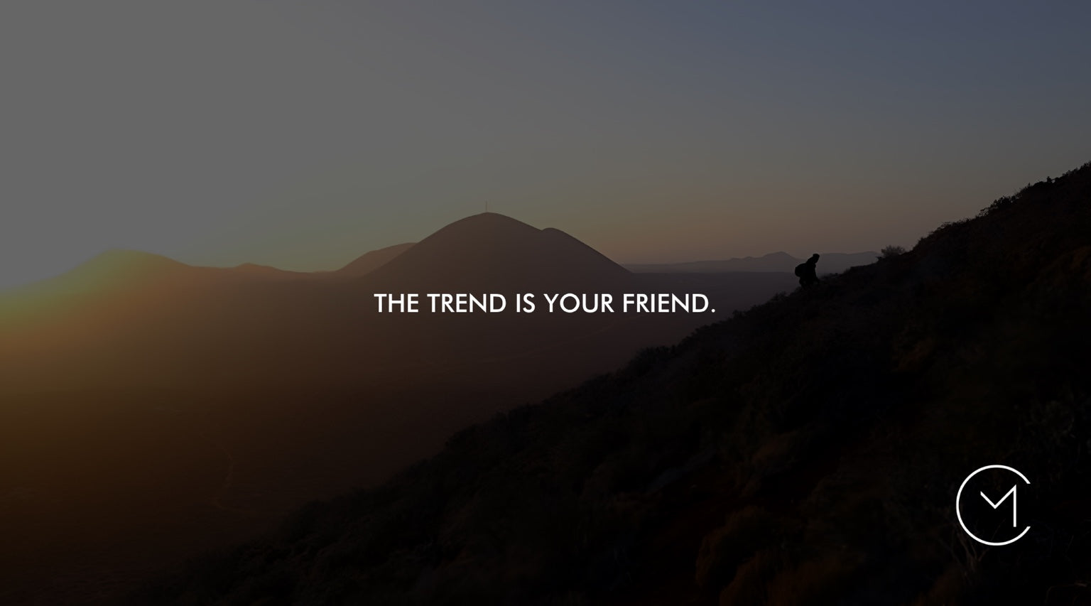 A silhouetted hiker climbs a mountain ridge at sunset, illustrating the trading principle that the trend is your friend.