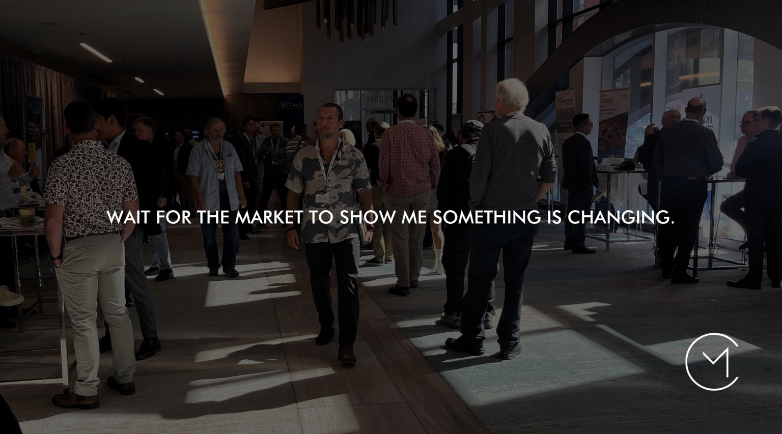 A man walks through a capital markets conference, illustrating the discipline of waiting for market momentum to show that something is changing.